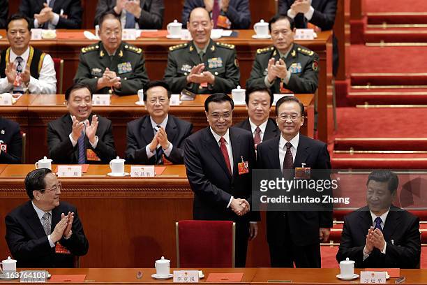 China's newly-elected Premier Li Keqiang shakes hands with former Chinese Premier Wen Jiabao near Chinese President Xi Jinping during the fifth...