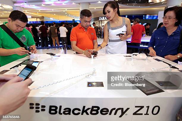 Sales assistant demonstrates the BlackBerry Z10 smartphone to a customer during the consumer launch of the device at the Central Park Mall in...
