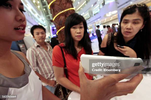 Sales assistant demonstrates the BlackBerry Z10 smartphone to customers during the consumer launch of the device at the Central Park Mall in Jakarta,...