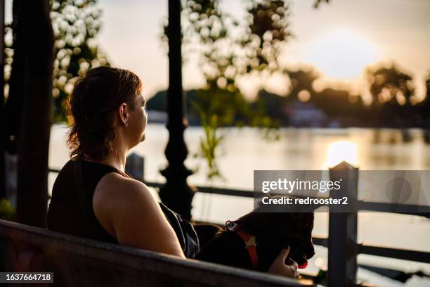 young confident woman walking a dog by the lake - mullet haircut woman stock pictures, royalty-free photos & images