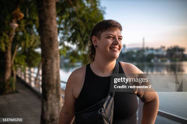 young confident woman walking a dog by the lake - mullet haircut woman stock pictures, royalty-free photos & images