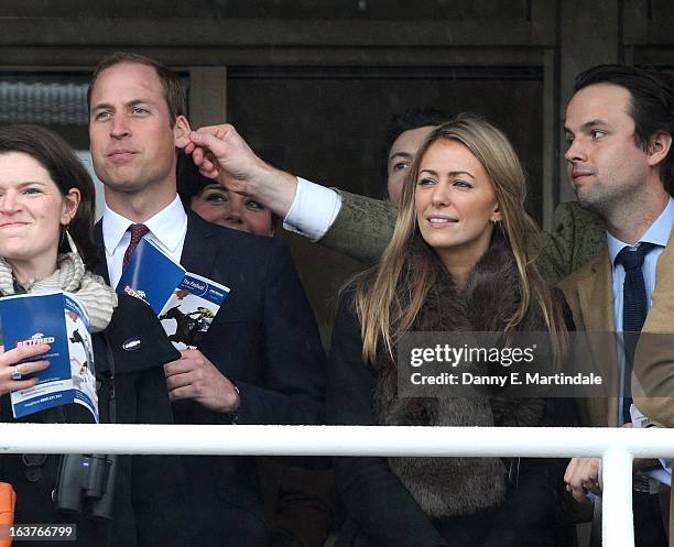Prince William, Duke of Cambridge has his ear pulled by a friend as he watches the races during day 4 of the Cheltenham Festival at Cheltenham...