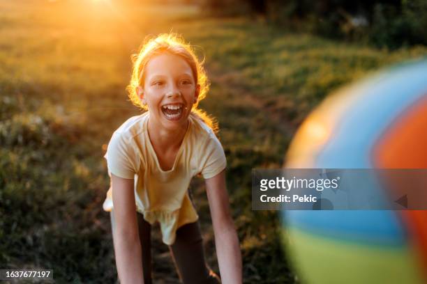 young cheerful girl playing volleyball outdoors - volleyball park stockfoto's en -beelden