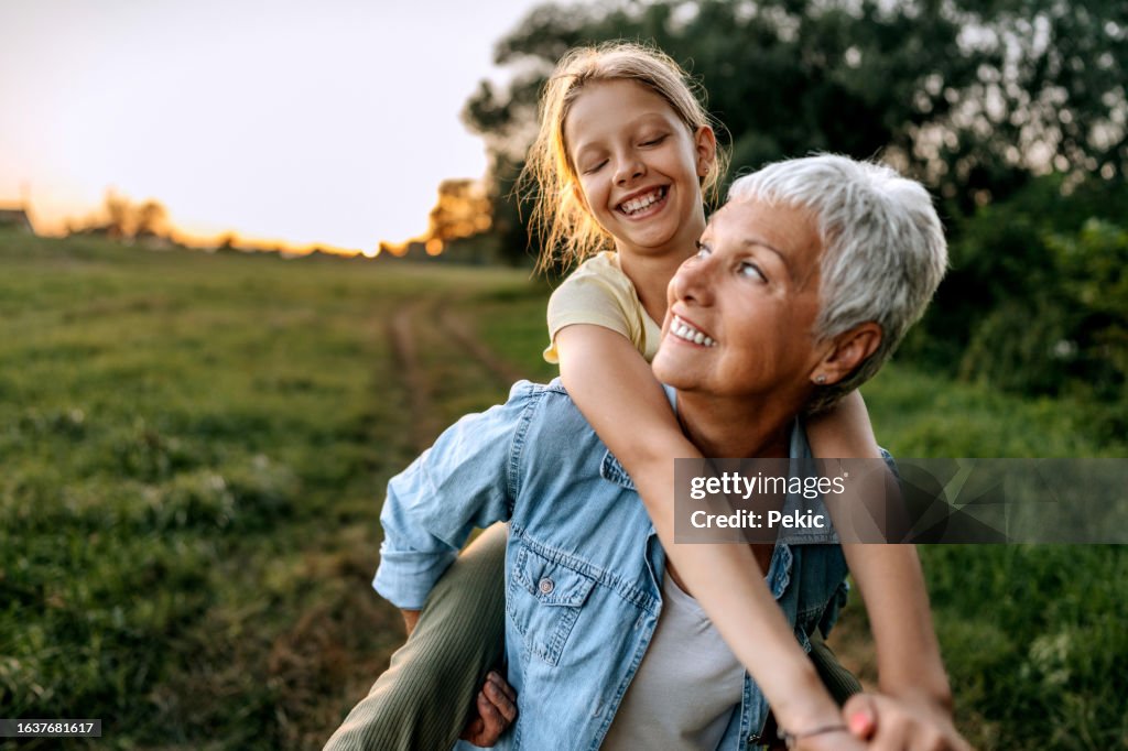 Grandmother carrying her granddaughter on back outdoors
