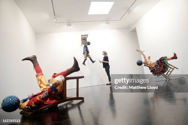 Curator poses alongside sculptures "Champagne Kid ", "Champagne Kid " and "Champagne Kid ", part of the Pop! exhbition by Yinka Shonibare, MBE at the...