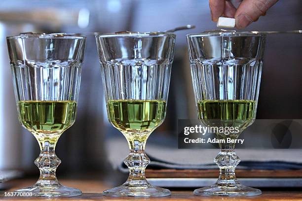 Martial Philippi, owner of the Absinth Depot shop, places a sugar cube onto an absinthe spoon atop a glass of absinthe on March 15, 2013 in Berlin,...