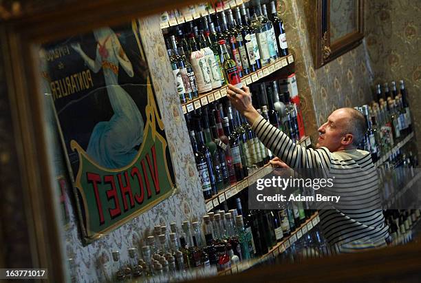 Martial Philippi, owner of the Absinth Depot shop, removes bottles of absinthe from a shelf on March 15, 2013 in Berlin, Germany. The highly...