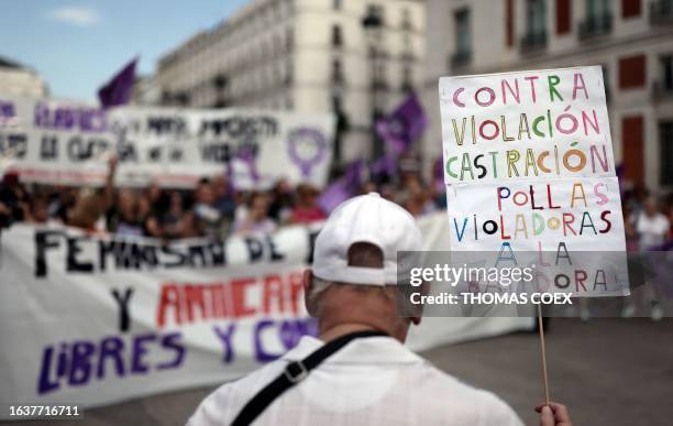 Man holds a placard reading "Against rape, castration. Rapist cocks to the grinder" during a protest against the suspended president of Spanish Royal...