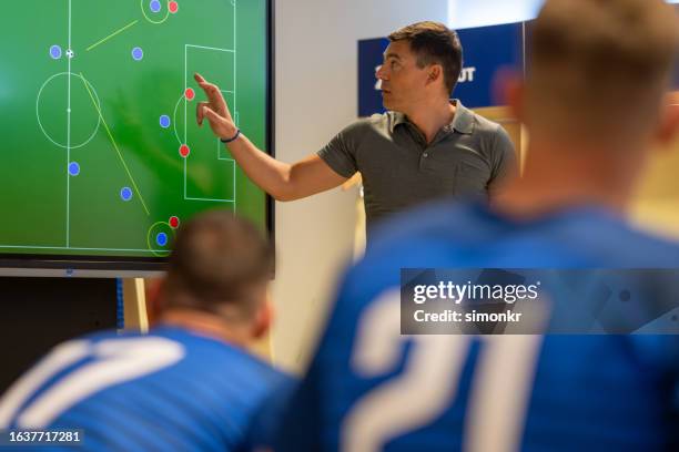 coach erklärt spielstrategie auf dem gerätebildschirm - umkleideraum stock-fotos und bilder