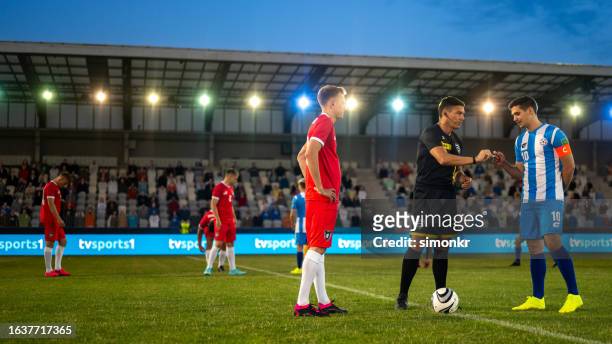 referee with team captions on football pitch - referee shirt stock pictures, royalty-free photos & images