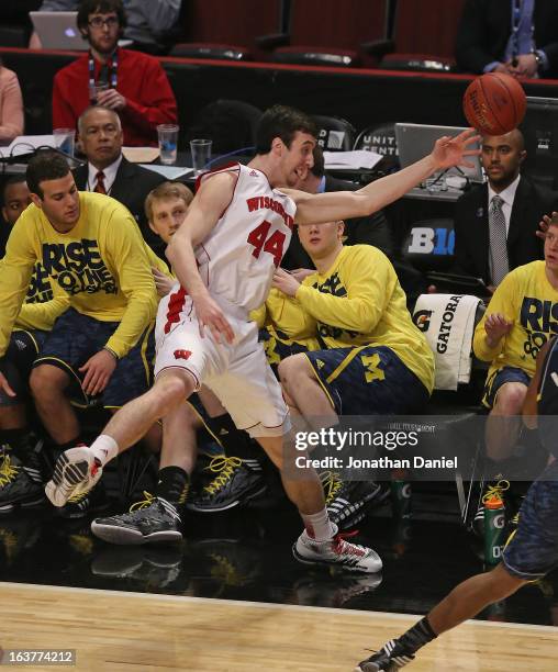 Frank Kaminsky of the Wisconsin Badgers tries to save the ball from going out of bounds in front of the Michigan Wolverine bench during a...