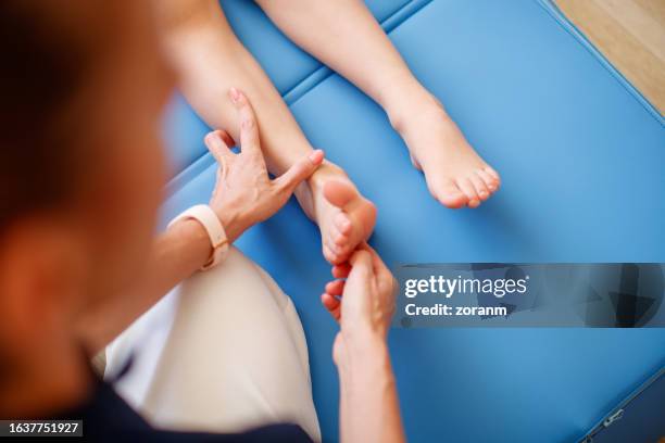 checking boy patient's primary reflexes on sole of his foot - voetzool stockfoto's en -beelden