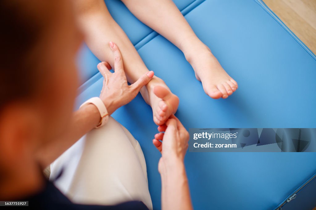 Checking boy patient's primary reflexes on sole of his foot