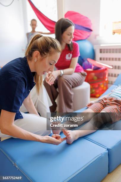 femme médecin vérifiant les réflexes primaires d’un patient garçon sur la plante de son pied - réflexologie photos et images de collection