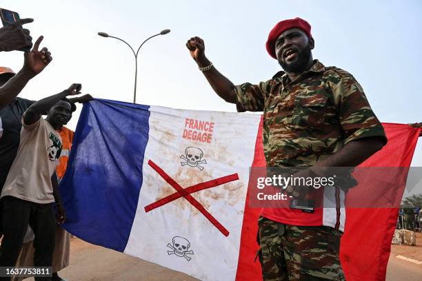 Supporters of Niger's National Council of Safeguard of the Homeland display a French national flag with a x-mark on during a protest outside Niger...