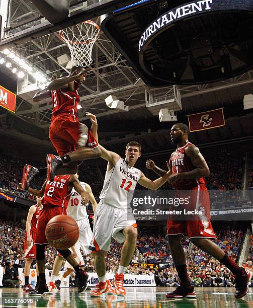 Joe Harris of the Virginia Cavaliers tries to get to a loose ball between teammates C.J. Leslie and Richard Howell of the North Carolina State...