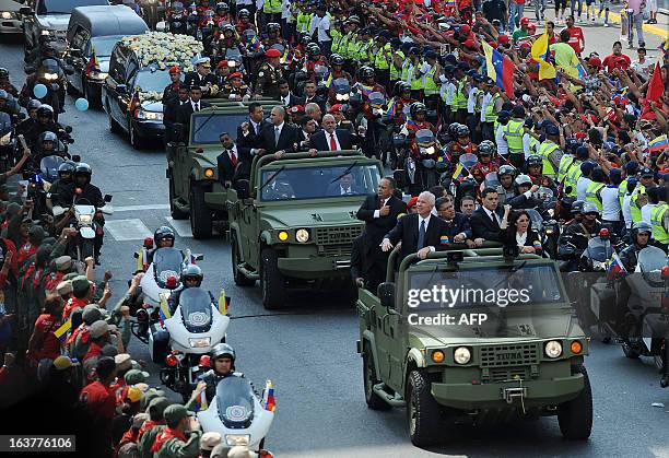 Venezuelan Government authorities and guests ride vehicles in front of the hearse carrying the remains of late Venezuelan President Hugo Chavez to...