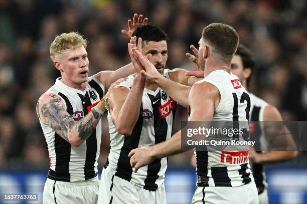 Scott Pendlebury of the Magpies is congratulated by team mates after kicking a goal during the round 24 AFL match between Essendon Bombers and...