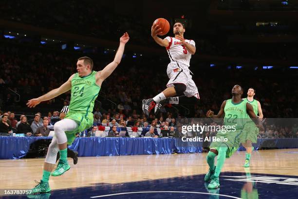 Peyton Siva of the Louisville Cardinals drives for a shot attempt against Pat Connaughton and Jerian Grant of the Notre Dame Fighting Irish during...