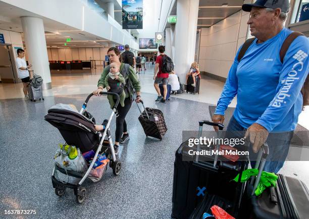 Katie Wood, of Westlake Village, makes her way at Southwest Airlines at LAX with her son, Owen in carriage, and son Bryce, 10 months, on her way with...