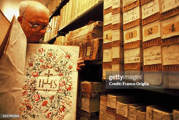 Jesuit father shows an ancient book featuring the symbol of the Society of Jesus taken at the historical archive of the Jesuit General Curia in 1991...