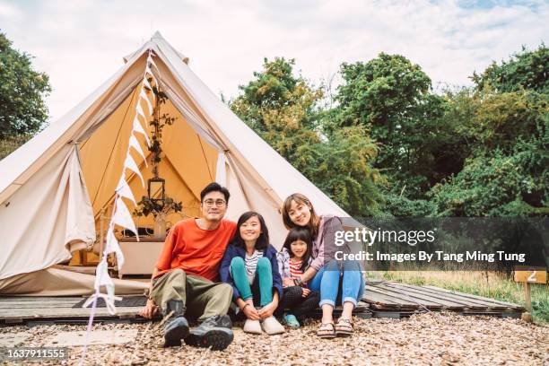 a happy family portrait of a young family sitti f outside a glamping bell tent during their camping vacation - thier stock pictures, royalty-free photos & images