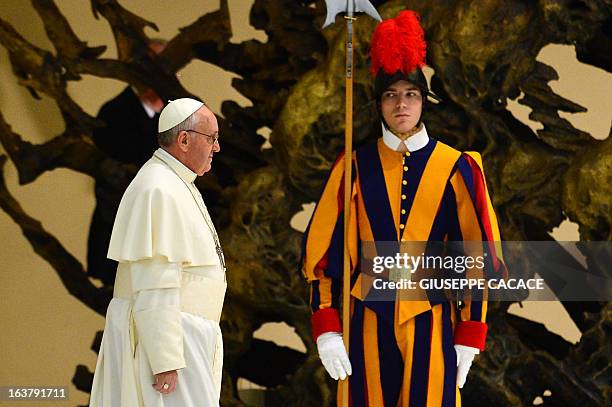 Swiss guard looks at Pope Francis as he arrives for a private audience to members of the media on March 16, 2013 at the Paul VI hall at the Vatican....