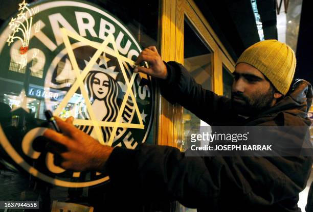 Lebanese protestor sticks a Jewish star of David on the window of a 'Starbucks Coffee' shop during a demonstration to call for a boycot of the coffee...