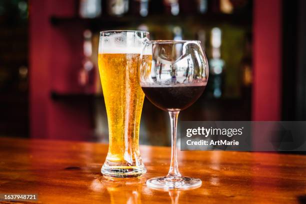 un verre de vin rouge et une pinte de bière sur un comptoir de bar - bière photos et images de collection