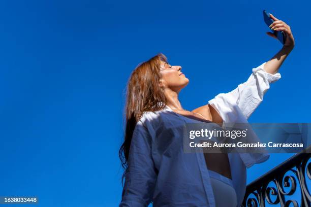 beautiful brunette girl posing with white shirt on the terrace of a house - open hair selfie stock pictures, royalty-free photos & images