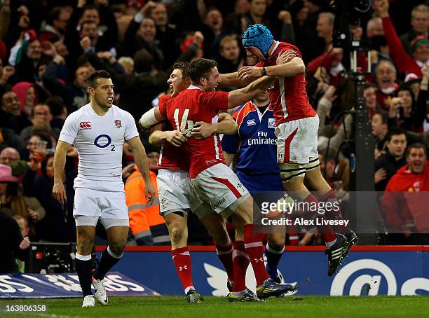 Alex Cuthbert of Wales celebrates with teammates Dan Biggar and Justin Tipuric after scoring his team's second try during the RBS Six Nations match...