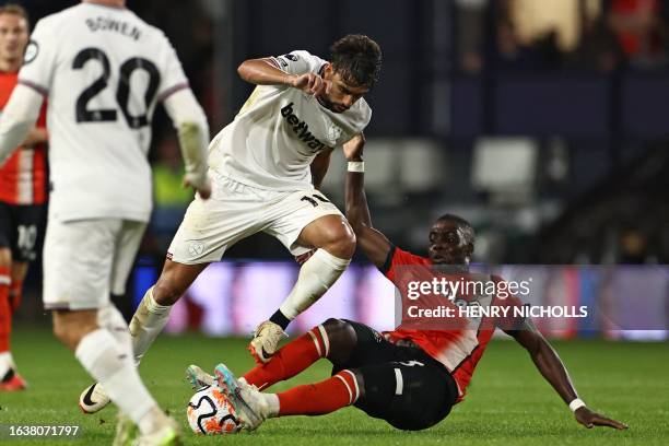 Luton Town's Zimbabwean midfielder Marvelous Nakamba tackles West Ham United's Brazilian midfielder Lucas Paqueta during the English Premier League...