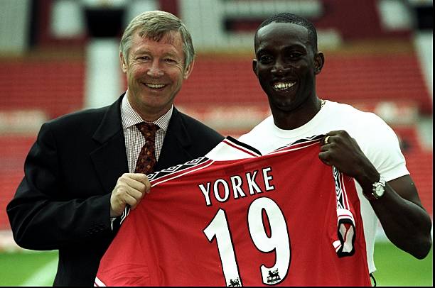 Dwight Yorke of Trinidad and Tobago receives his shirt from manager Alex Ferguson after completing his 12 million pound transfer to Manchester United...