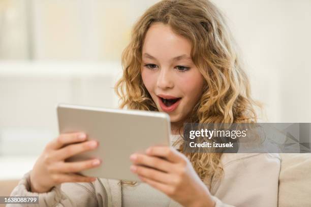 surprised teenage girl using digital tablet at home - enthusiastic stock pictures, royalty-free photos & images