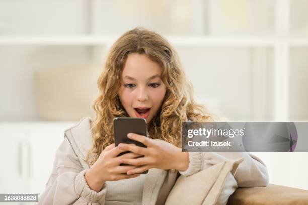surprised teenage girl using smart phone at home - gasping stock pictures, royalty-free photos & images