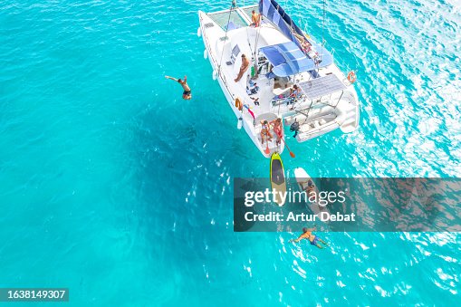 Aerial view of a group of friends having fun in the water sailing with catamaran on the Formentera island in Spain. Aerial view of a group of friends having fun in the water sailing with catamaran on the Formentera island in Spain.