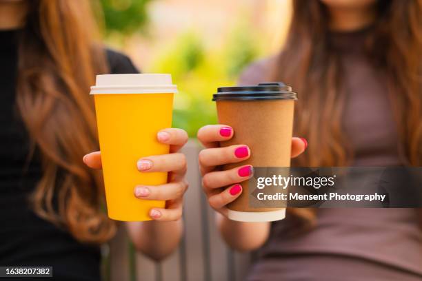 two female twin sisters hands holding recyclable takeaways coffee cup outdoors, close-up - takeaway coffee stock pictures, royalty-free photos & images