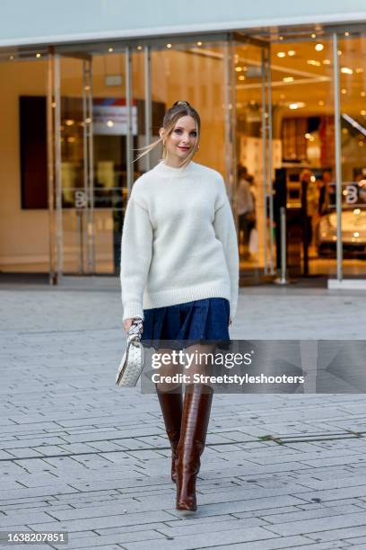 Model Anna Hiltrop, wearing a white pullover La Maille Pavane with Alpaka by Jacquemus, a dark blue jeans skilt by Closed, a white bag and brown...