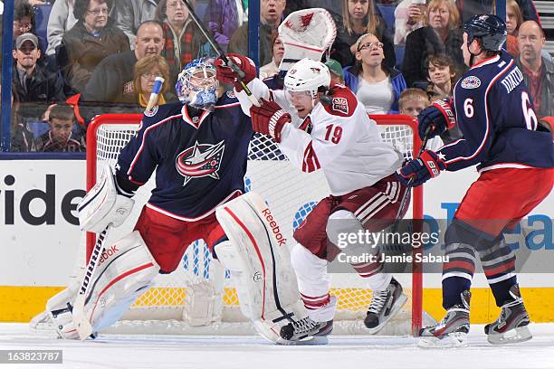 Shane Doan of the Phoenix Coyotes is hit by a shot while skating in front of goaltender Sergei Bobrovsky of the Columbus Blue Jackets during the...