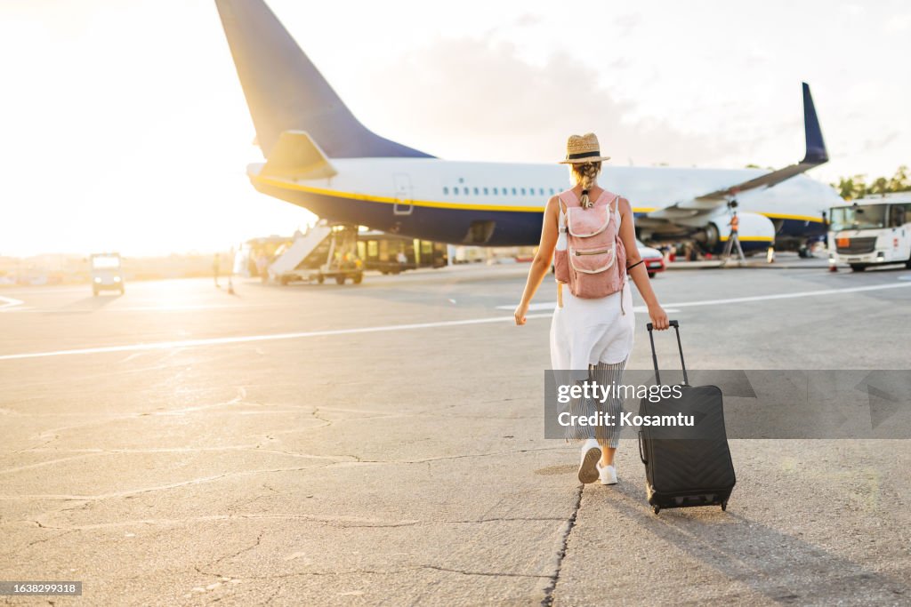 Rückansicht einer Frau, die auf das Flugzeug zugeht, bereit, einzusteigen und ihren Urlaub zu beginnen