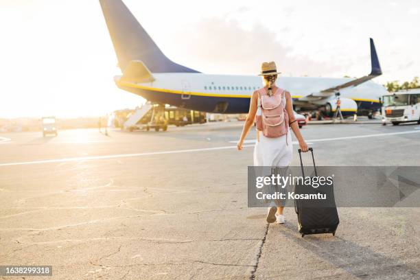 back view of a woman walking towards the plane, ready to board and begin her vacation - cheap day excursions stock pictures, royalty-free photos & images