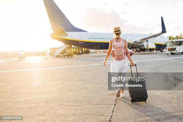 back view of a woman walking towards the plane, ready to board and begin her vacation - international day one stock pictures, royalty-free photos & images