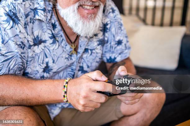 close-up of the controller of a 50-year-old badass-looking man happily celebrating success playing video games in his living room. - handsome 50 year old men imagens e fotografias de stock