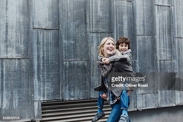 happy mother carrying son piggyback - monoparental fotografías e imágenes de stock