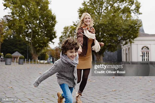 happy mother and son running outdoors - madre-corriendo fotografías e imágenes de stock