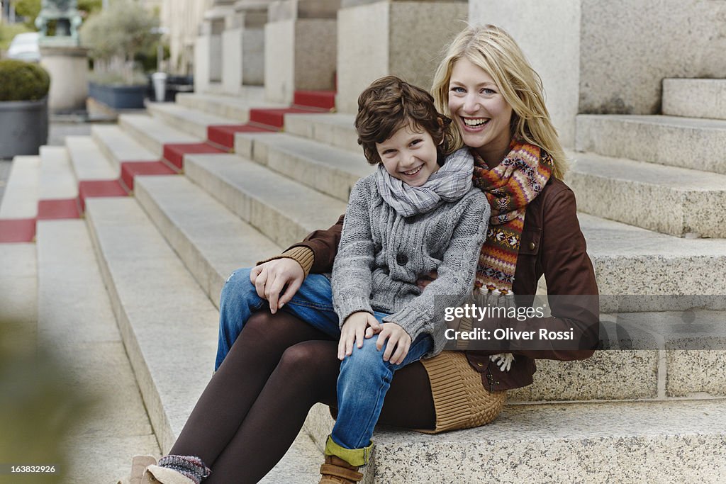 Happy mother and son sitting on stairs