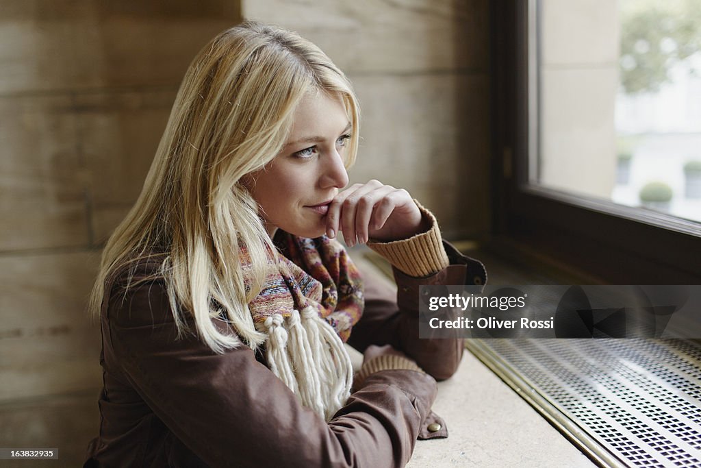 Blond young woman looking out of window