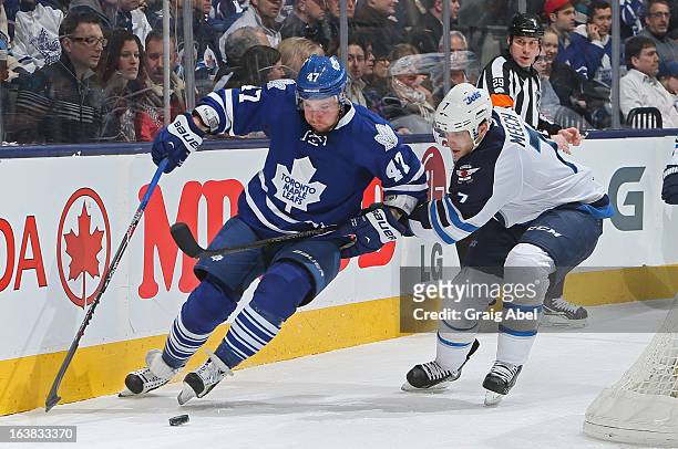 Leo Komarov of the Toronto Maple Leafs battles for the puck with Derek Meech of the Winnipeg Jets during NHL game action March 16, 2013 at the Air...