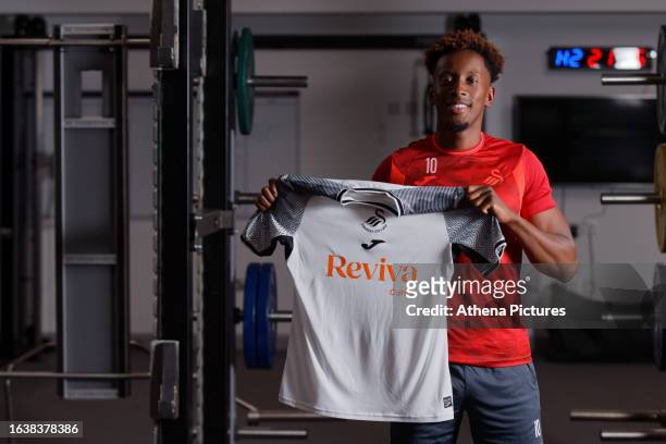 Jamal Lowe poses for a picture with a home shirt after signing a contract with Swansea City AFC at tFairwood Training Ground on September 01, 2023 in...