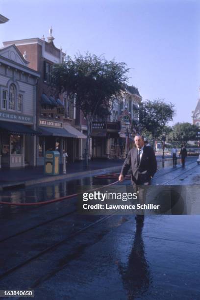 American businessman, animator, and director Walt Disney walks along a street in the Disneyland theme park, Anaheim, California, 1964.
